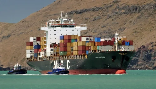 A container ship next to a tugboat. 