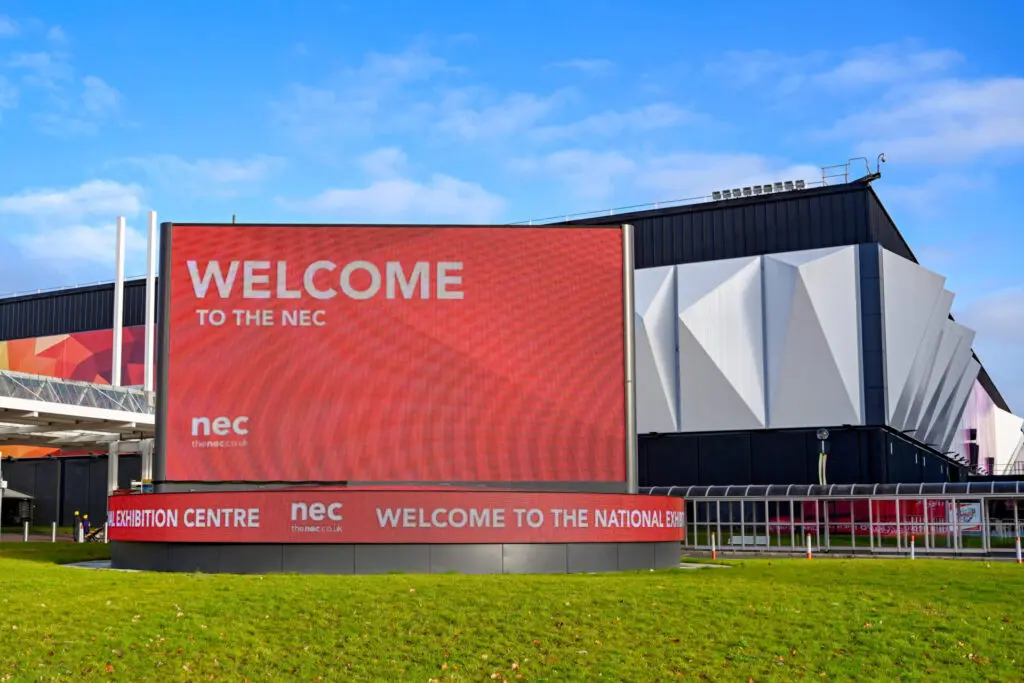A red digital sign outside the NEC in Birmingham welcoming visitors.