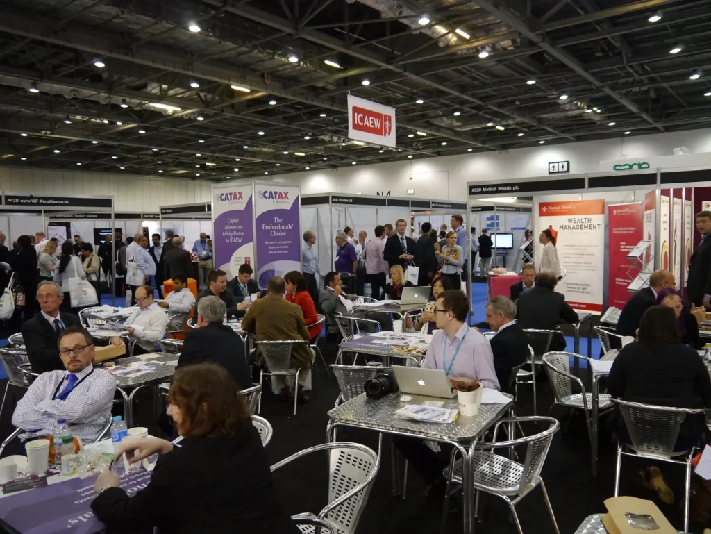 Multiple tables, exhibition stands, and guests at an accounting trade show. 