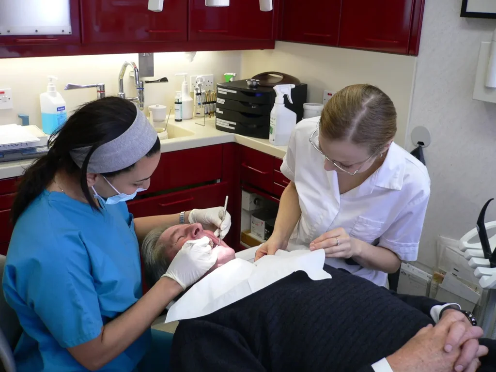 A dentist and her assistant work on a patient's mouth. 