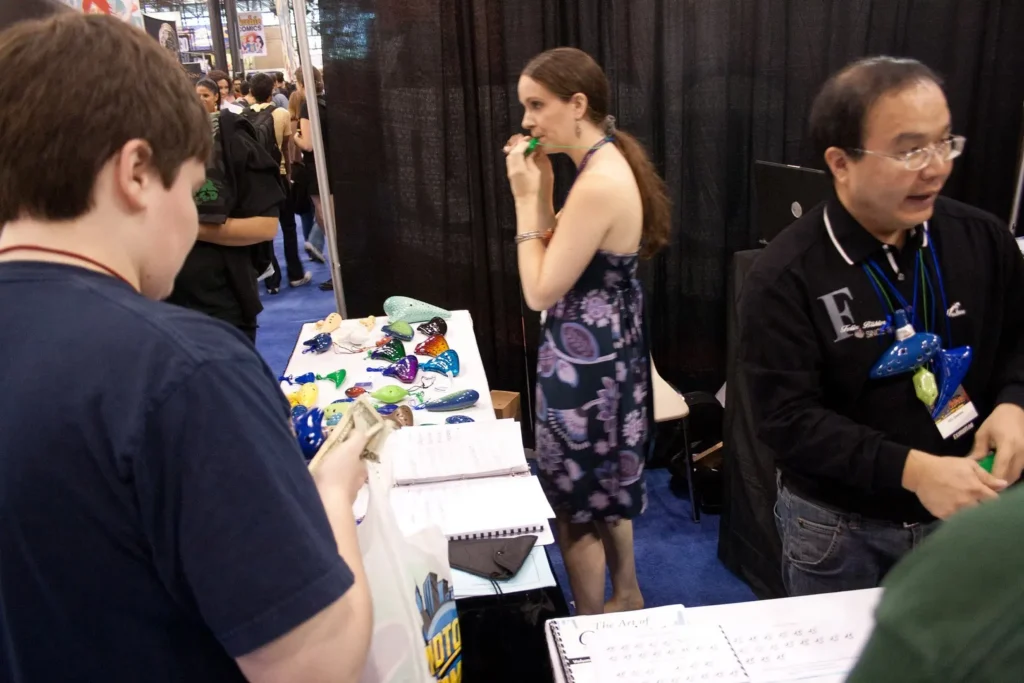 People interacting with staff at a small exhibition stand.