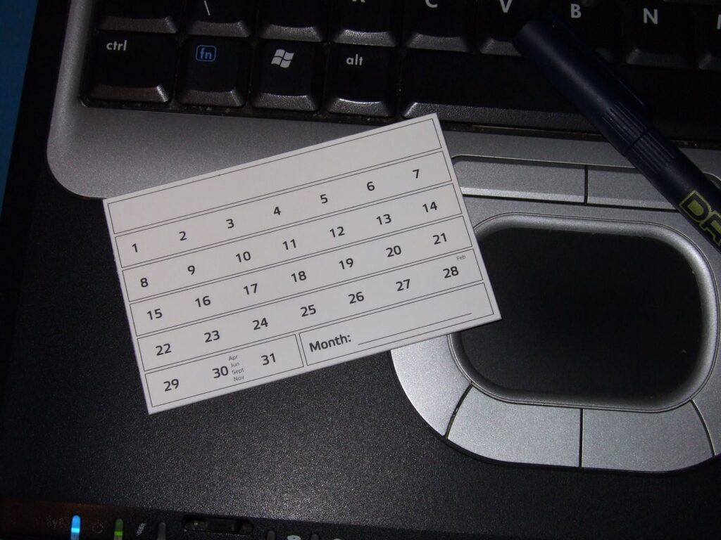 A small write-in paper calendar for February sitting on a laptop. 