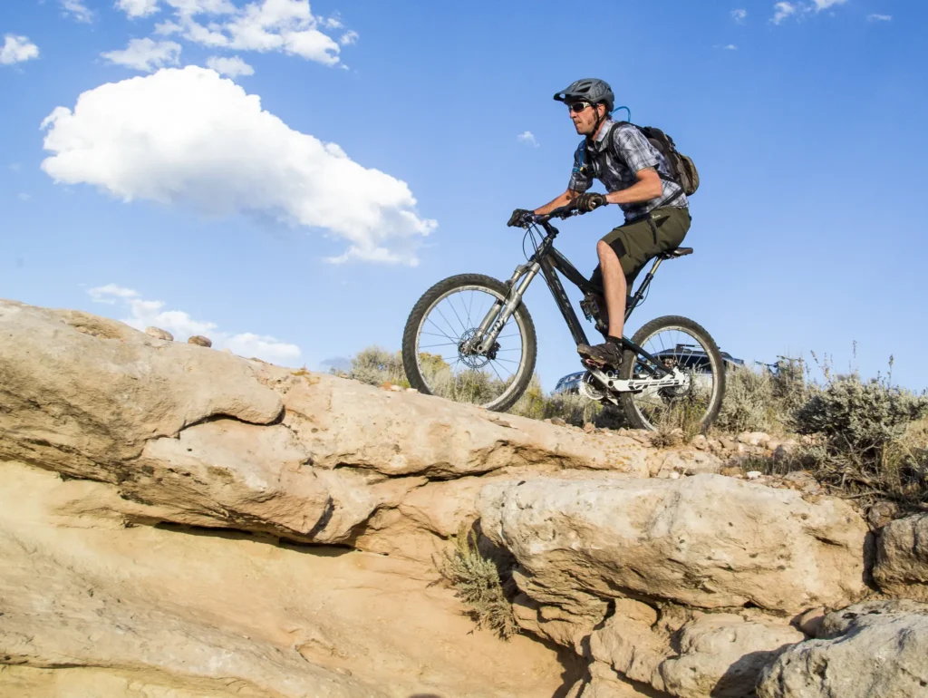 A man rides his bike up a rocky slope.