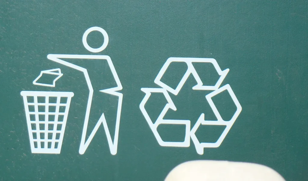 A white recycling sign on a green background. 