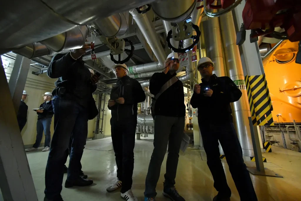 Workers wearing safety gear and inspecting some valves.