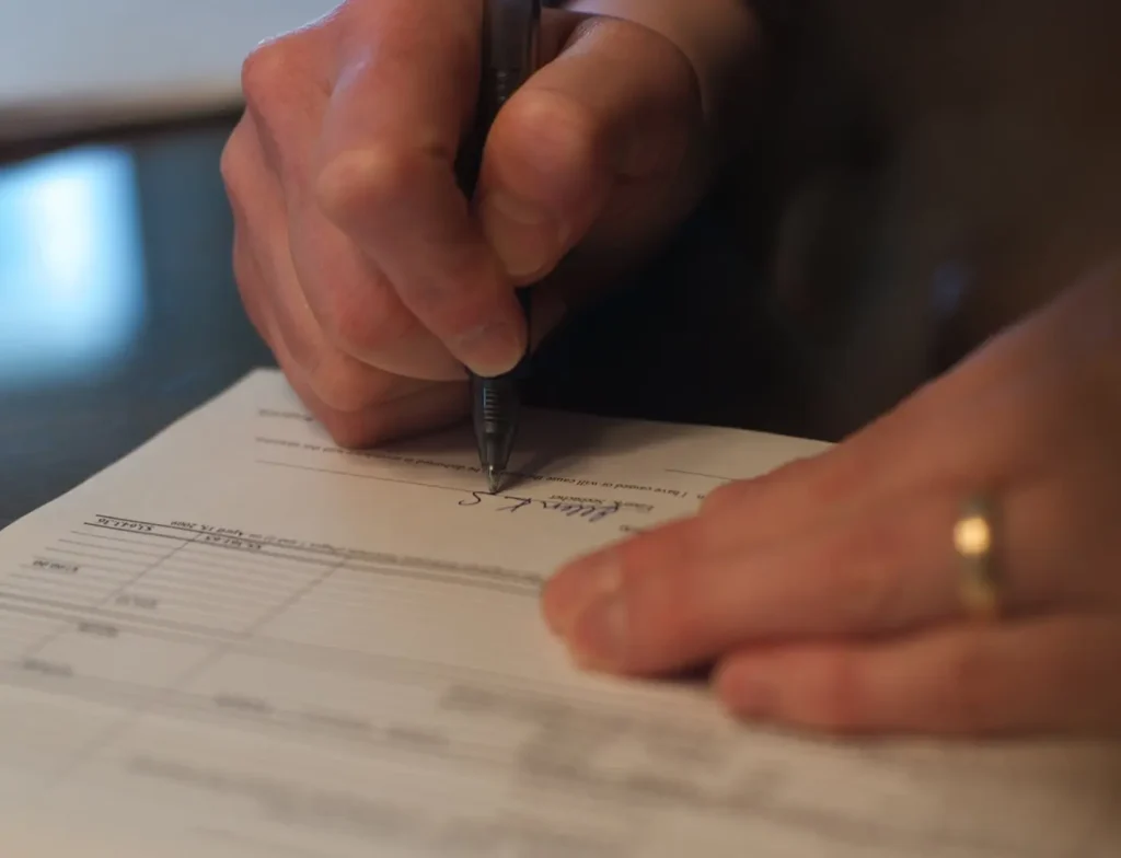 A person signs their name on a form.
