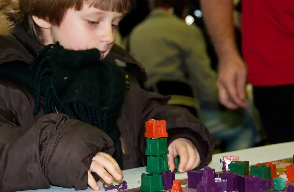 A child playing a tabletop game with pieces. 