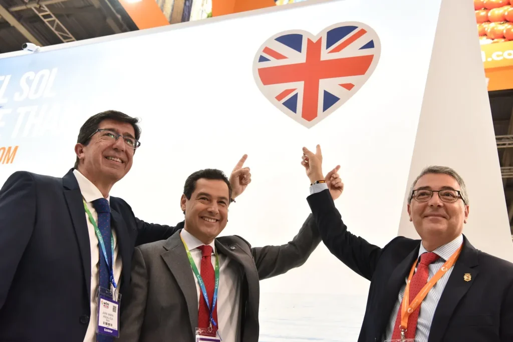 Three visitors at a WTM expo point to the British stand, which features the Union Jack inside a heart.