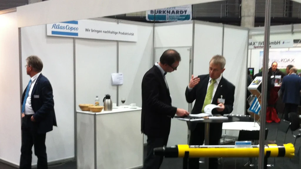 Professionals speak at a shell scheme stand. 