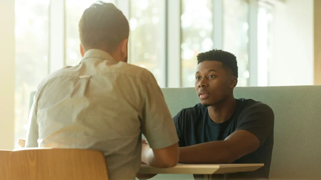 Two people sitting and talking to one another.